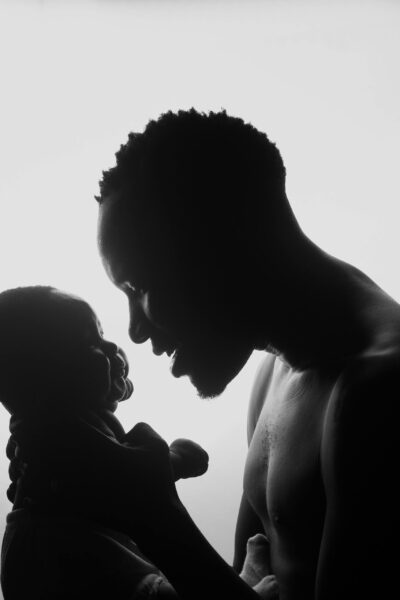 papa portant son bébé papa tenant son nouveau-né sous les aisselles, regard rempli d'amour et de tendresse