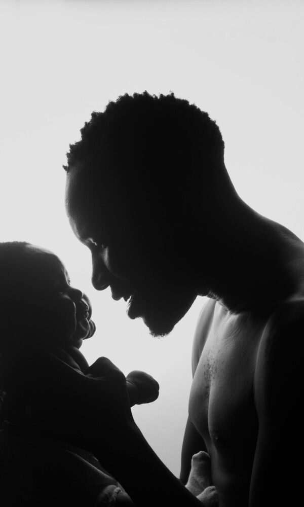 papa portant son bébé papa tenant son nouveau-né sous les aisselles, regard rempli d'amour et de tendresse